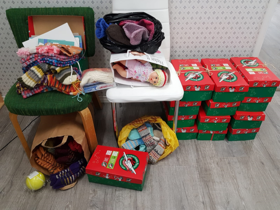 Kuvassa Joulun lapsi -kenkälaatikkoja ja niihin pakattavia tavaroita eli tässä villasukkia ja nukke.