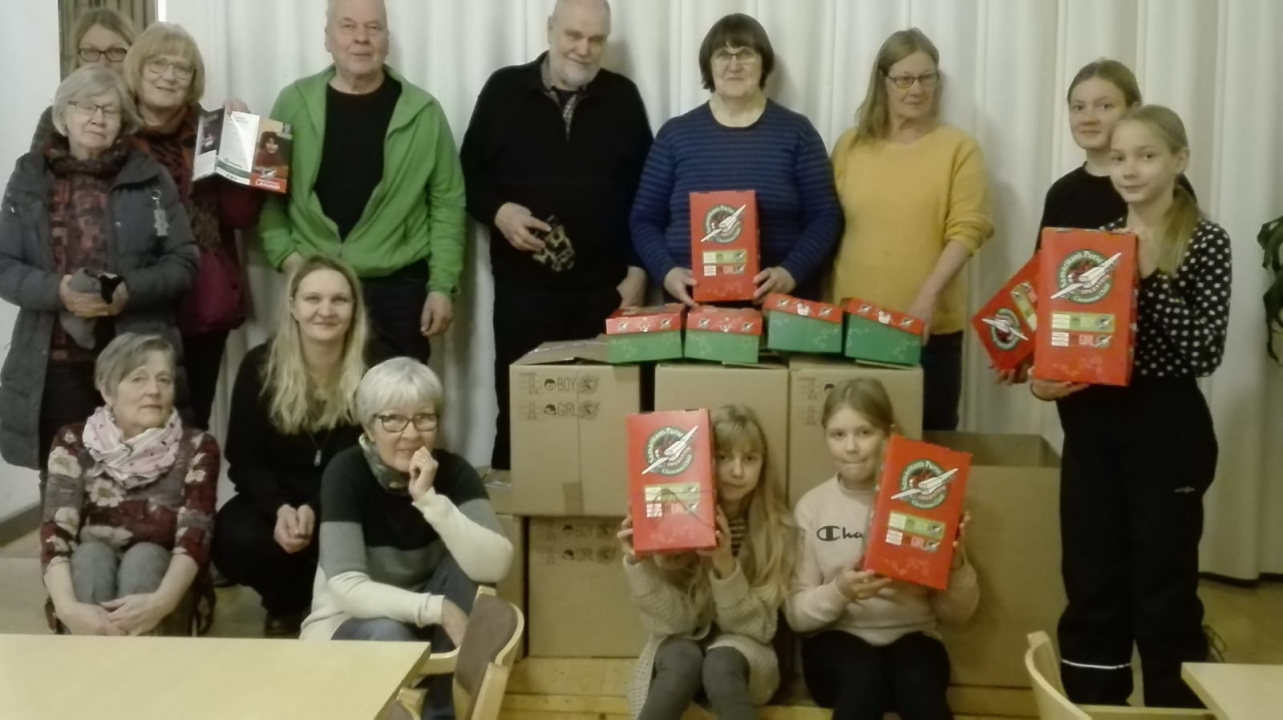 Kuva menneiltä vuosilta. Siinä on Joulun lapsi -pakettien tekijöitä valmiiden pakettien kanssa Kyyjärven seurakuntasalissa.