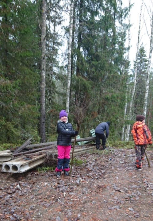 Lapsi seisoo ulkona luuta kädessä.