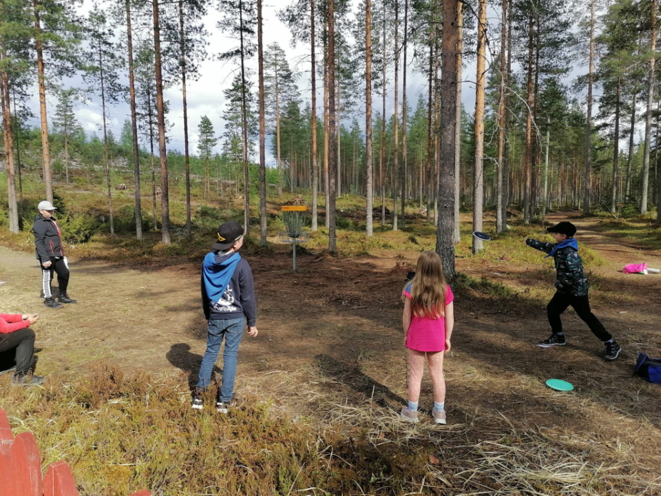 Lapset heittävät frisbeekiekkoa koriin