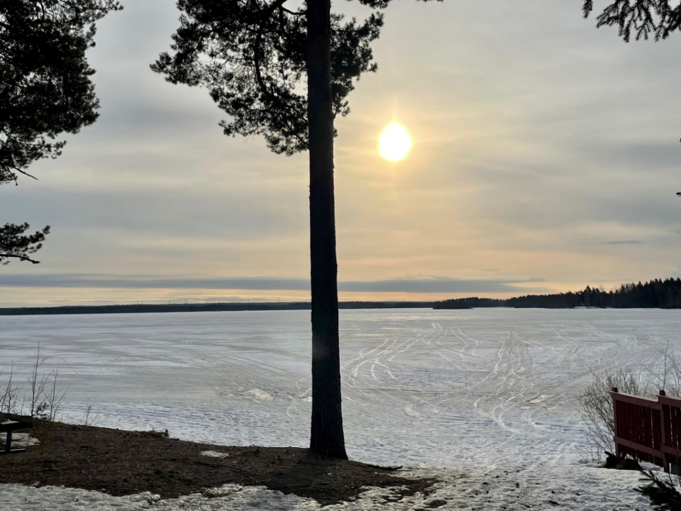 Auringonnousu jäisen järven takaa.