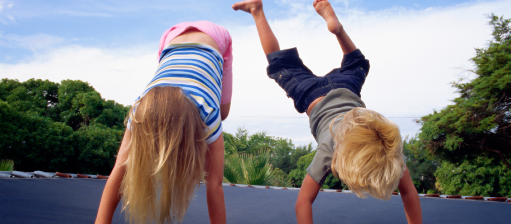 kaksi lasta pääalaspäin trampoliinilla