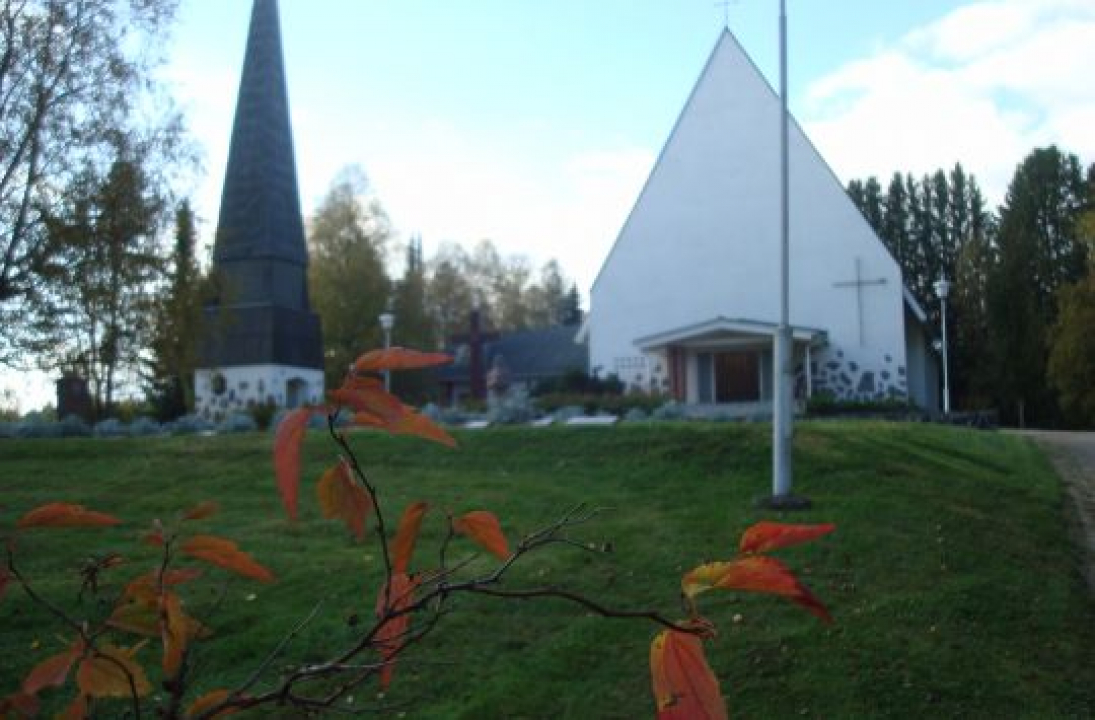 Kyyjärven kirkko ja tapuli, etualalla puun oksa ruskanvärisin lehdin.