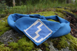 Kuvassa on kyypartion sininen huivi sammalaisen kiven päällä